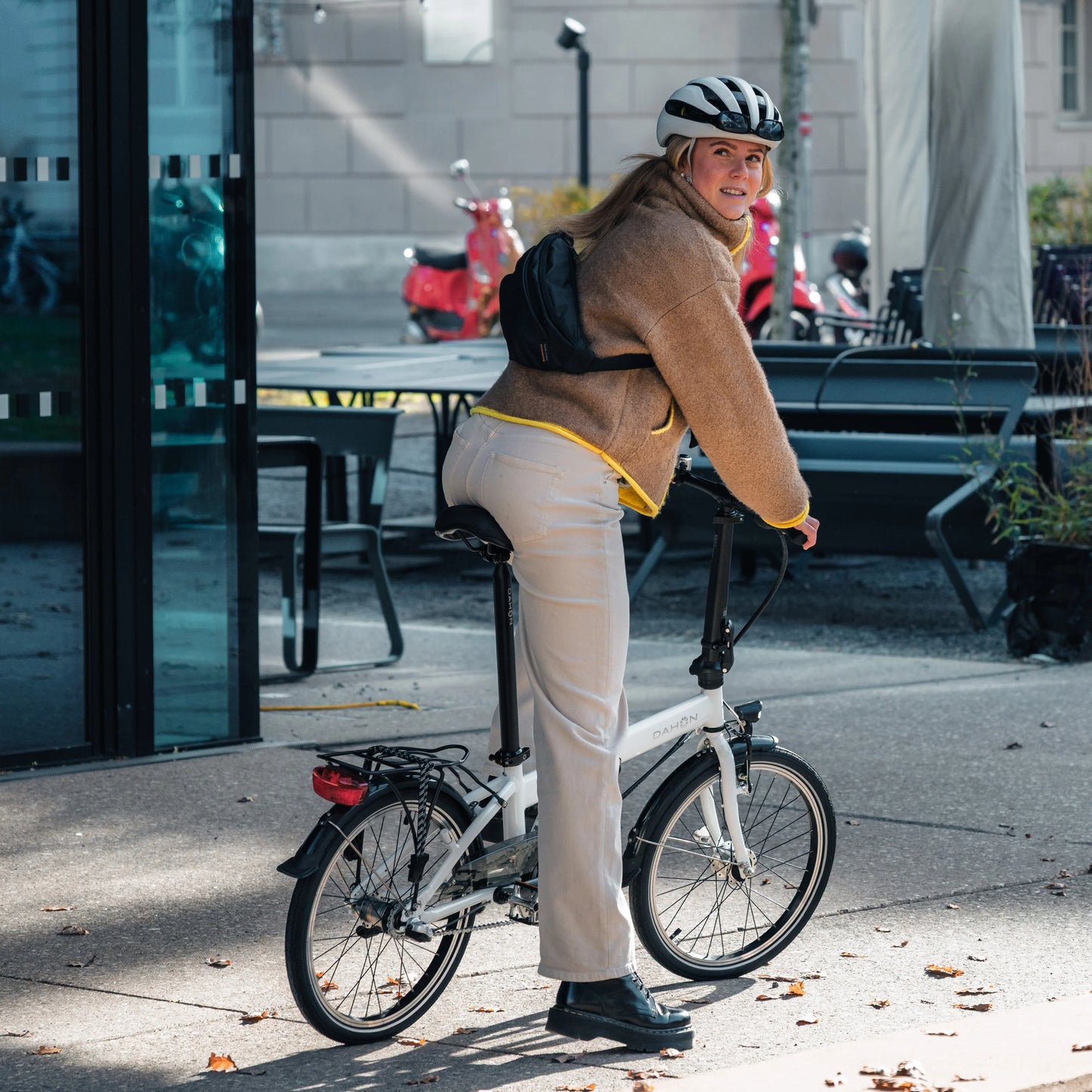 Person with a bicycle Dahon Hit i3 on a sidewalk in an urban setting